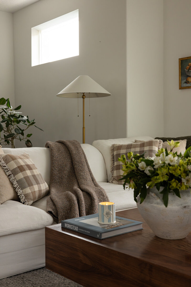 A close-up image of a modern transitional living room with a white couch, floor lamp, and a styled coffee table with florals