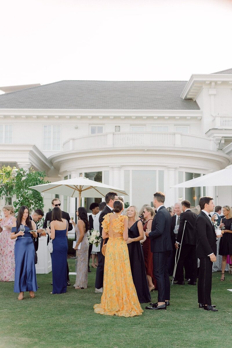 wedding guests in black tie gather for cocktail hour outside