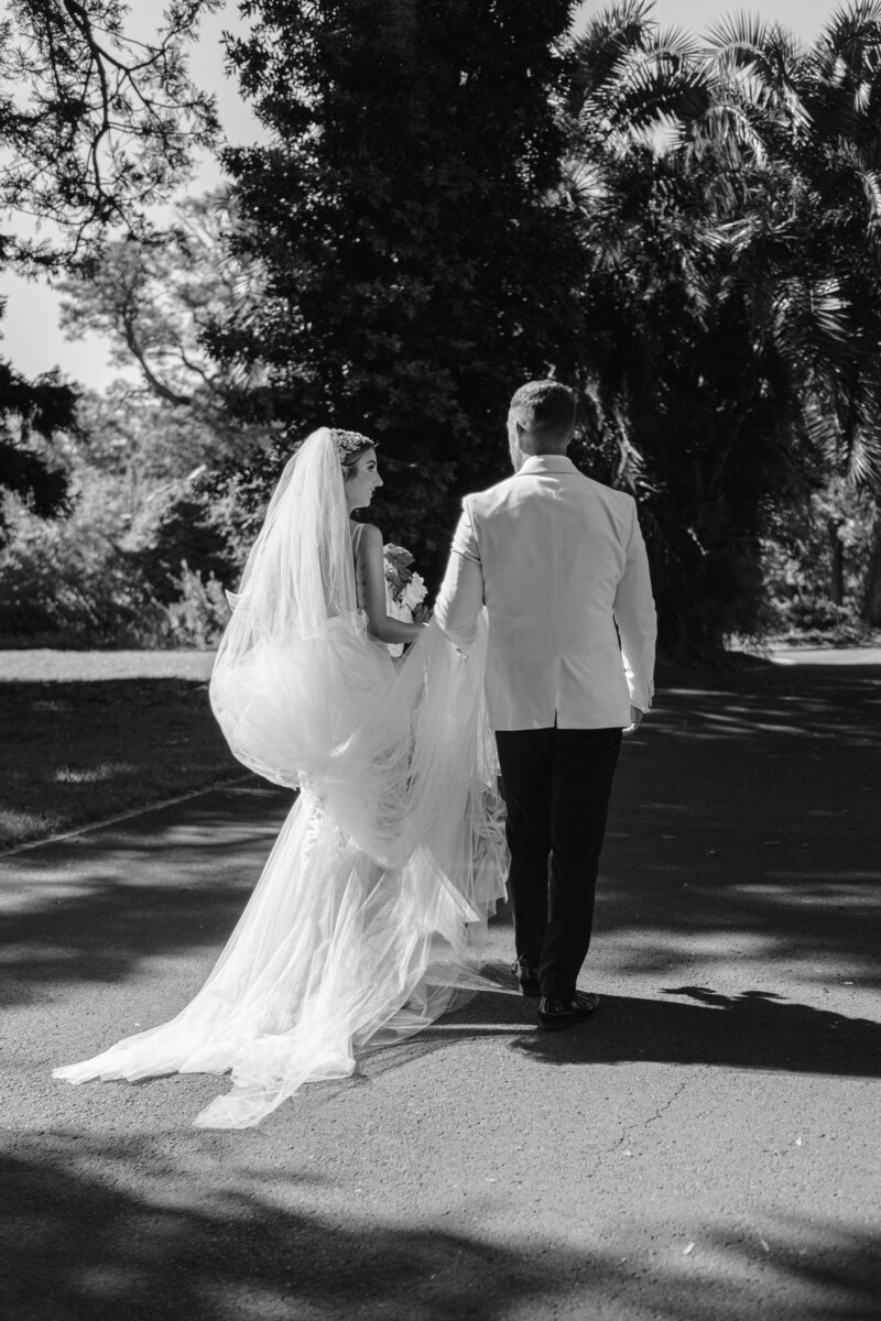 Bride draped in her veil, holding her boquet of white roses