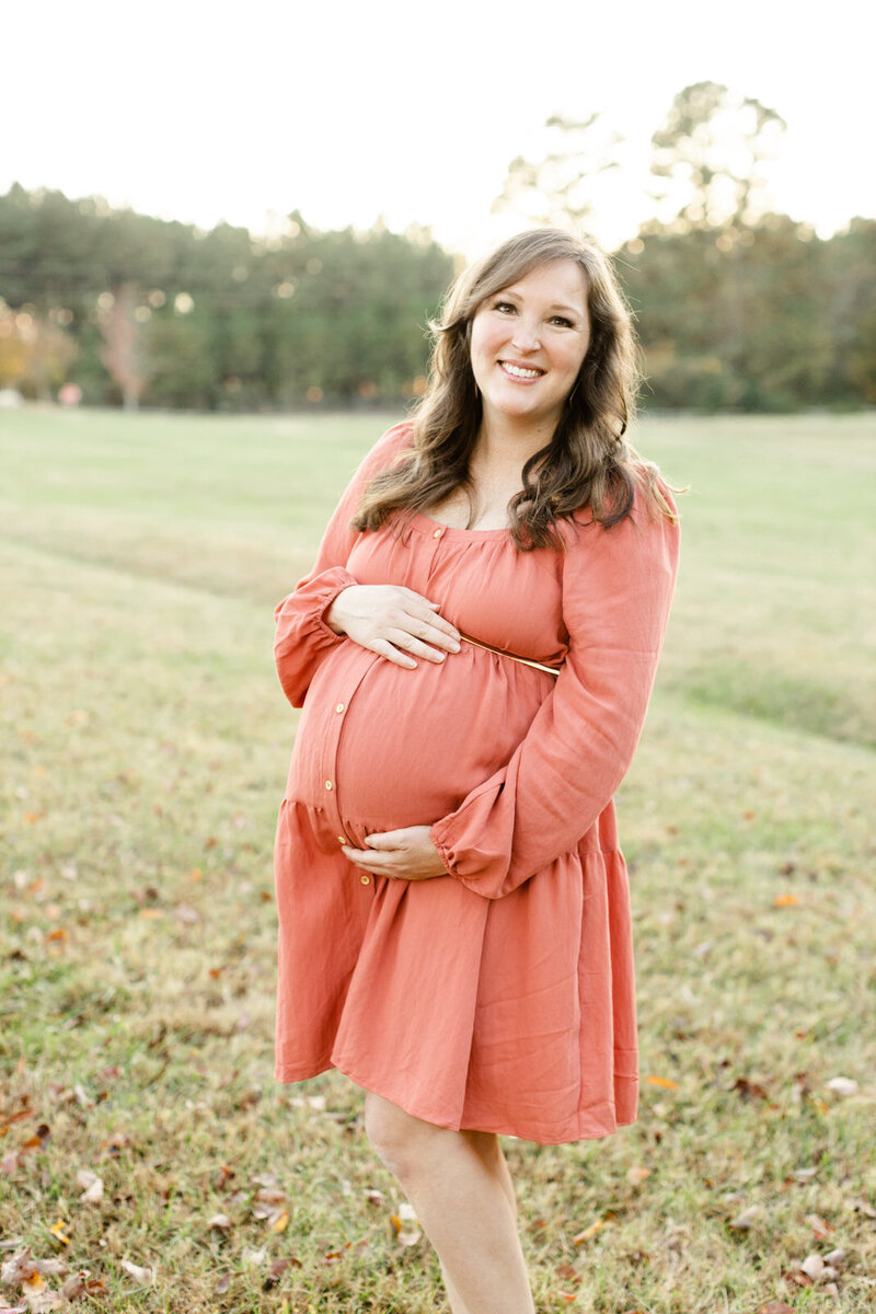 Pregnant mom poses with hands on baby bump during maternity session