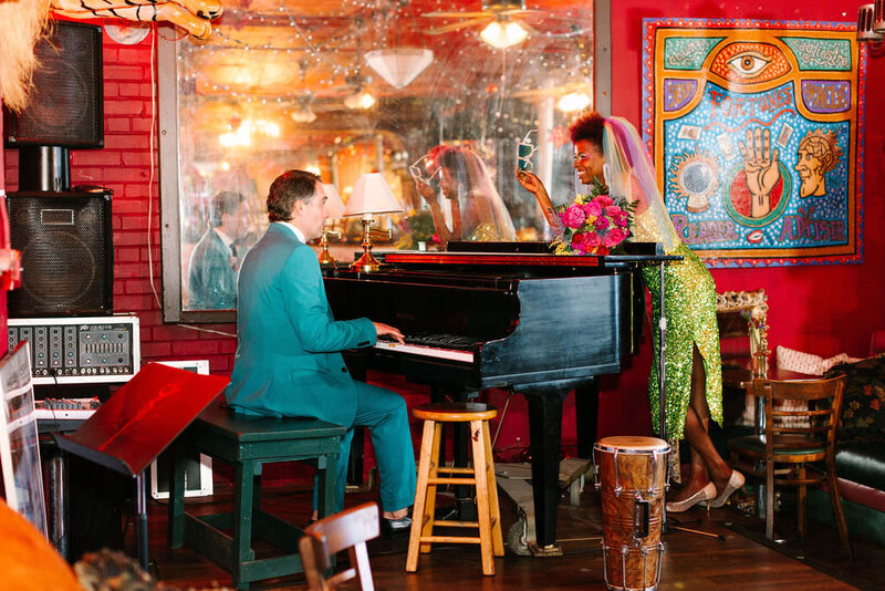 A man sitting at a piano with a woman leaning on it.
