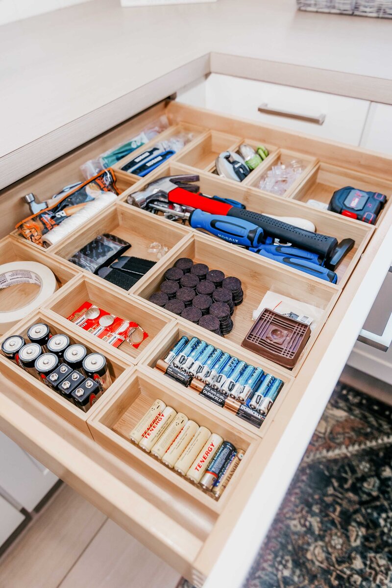 An open drawer showing organized batteries, tools and tape