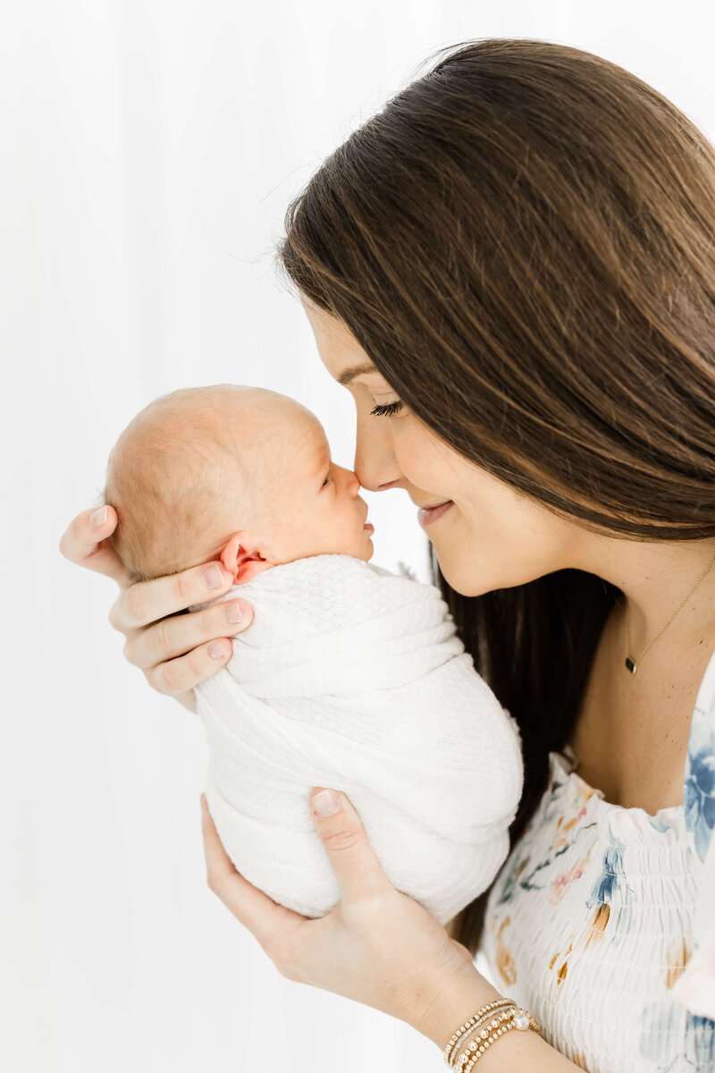 Woman holding newborn baby touching noses while smiling during newborn photography session in Dothan Alabama Photography session