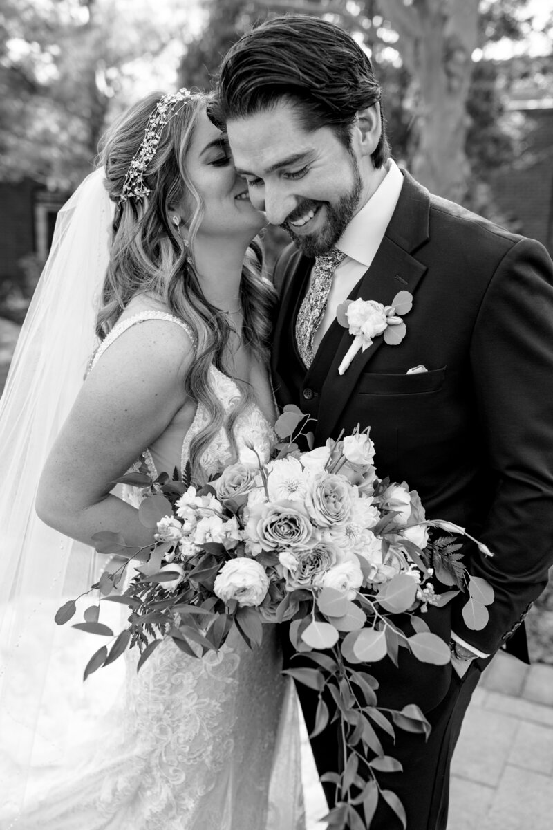 black and white image of bride whispering to groom