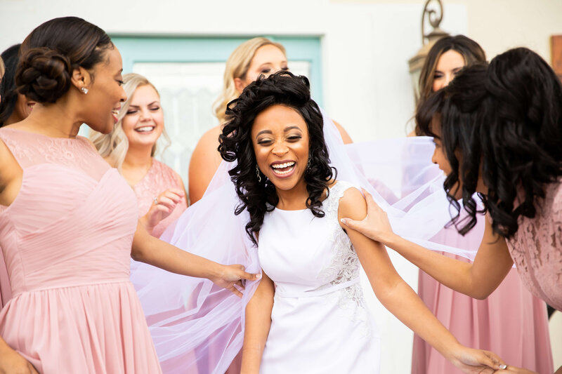 Bride in the middle of bridesmaids wearing pink and purple dresses