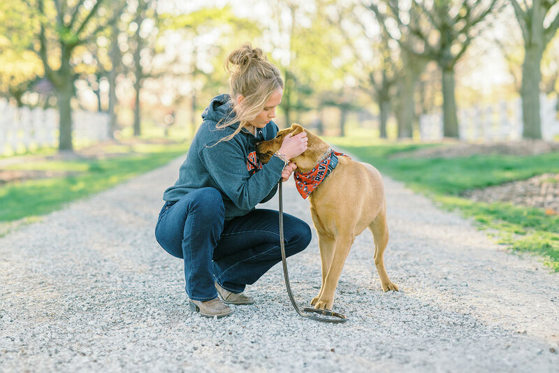 Girl wearing gray hoodie and blue jeans playing with her dog at Danada House in Wheaton, IL