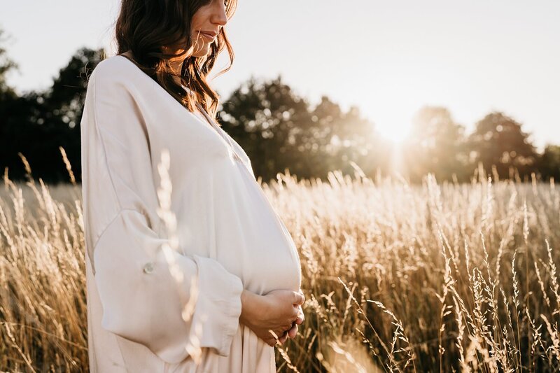 zwangerschapsfoto tijdens golden hour in een veld