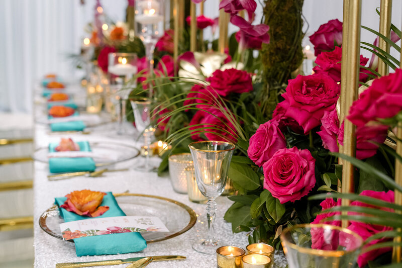 Vibrant event table setting with roses and gold candles