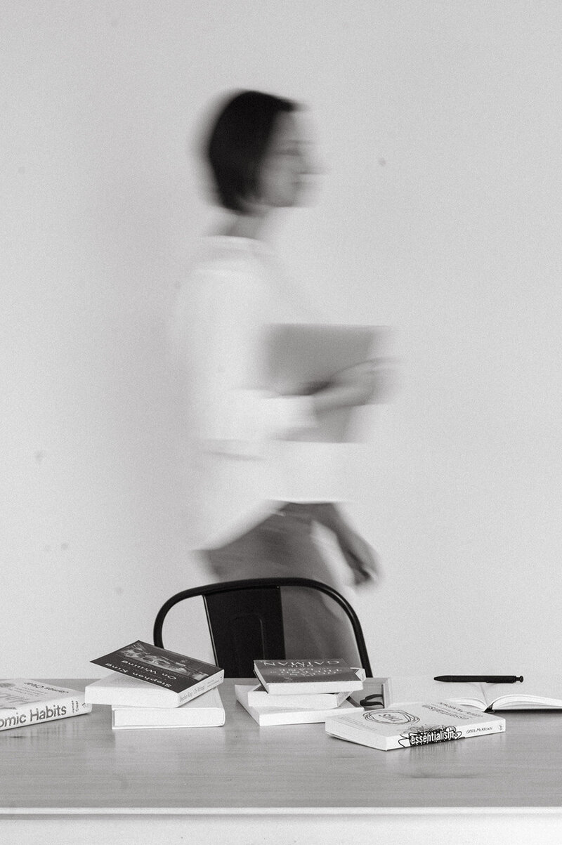 blurry effect image of women walking across an office with a book