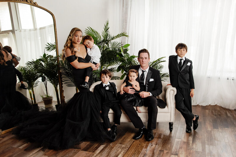 st-louis-family-photographer-family-of-six-wearing-tuxes-and-black-gowns-in-front-of-large-mirror-and-window