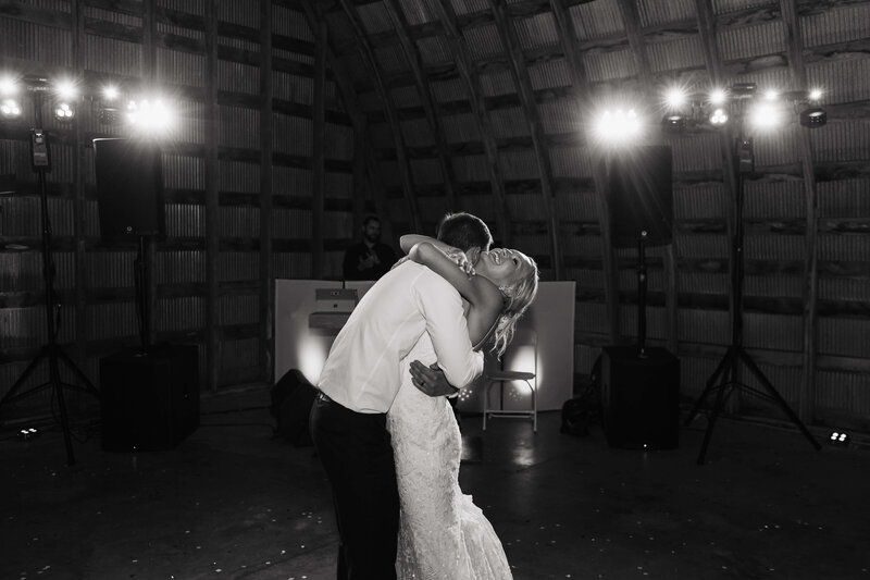 Bride throws her head back and her arms around her husband during newlywed first dance