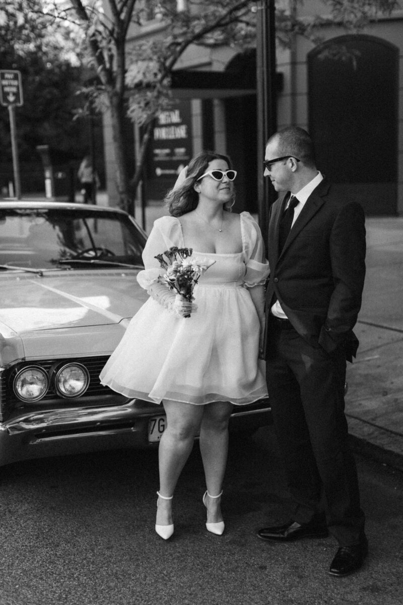 Couple stating in front of a vintage car after their ceremony