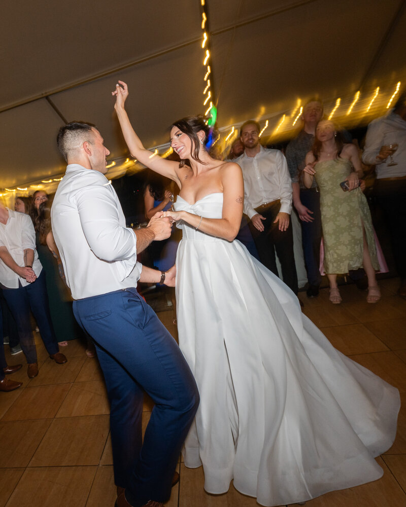 Bride and groom dancing under a tent during their wedding reception with a slight blur to show movement