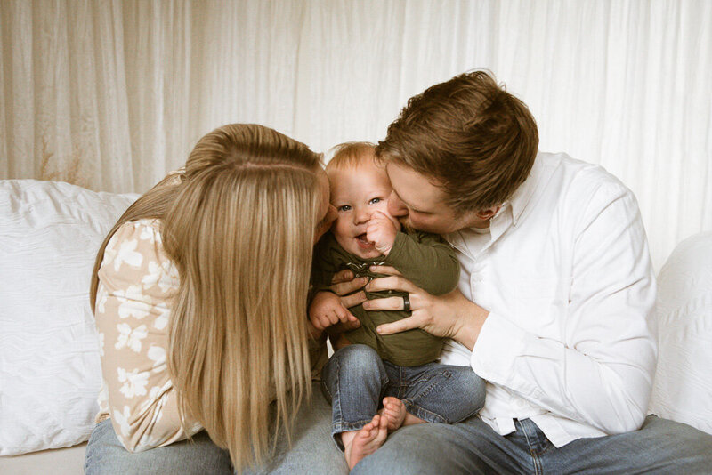 happy couple kissing baby on cheeks