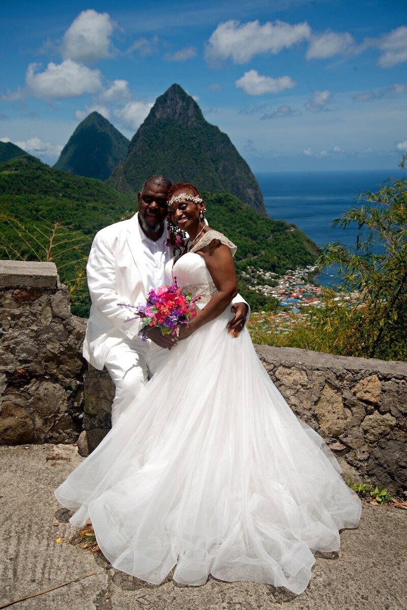 Bride and groom embrace on stone bridge in St. Lucia.