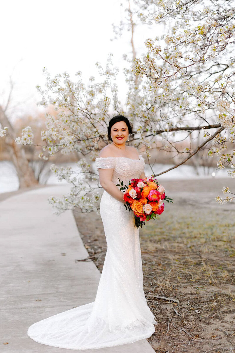 Bride wearing an off shoulder wedding dress holding a colorful bouquet