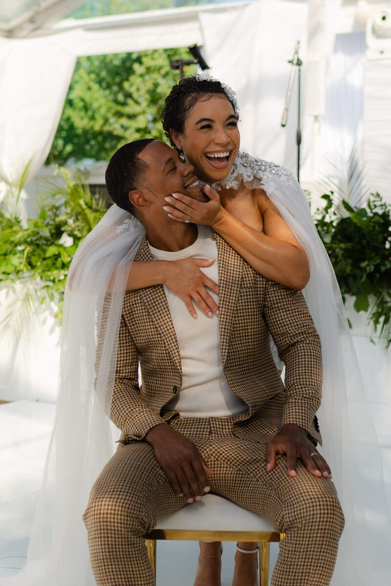 a smiling bride and groom hold each other and laugh together