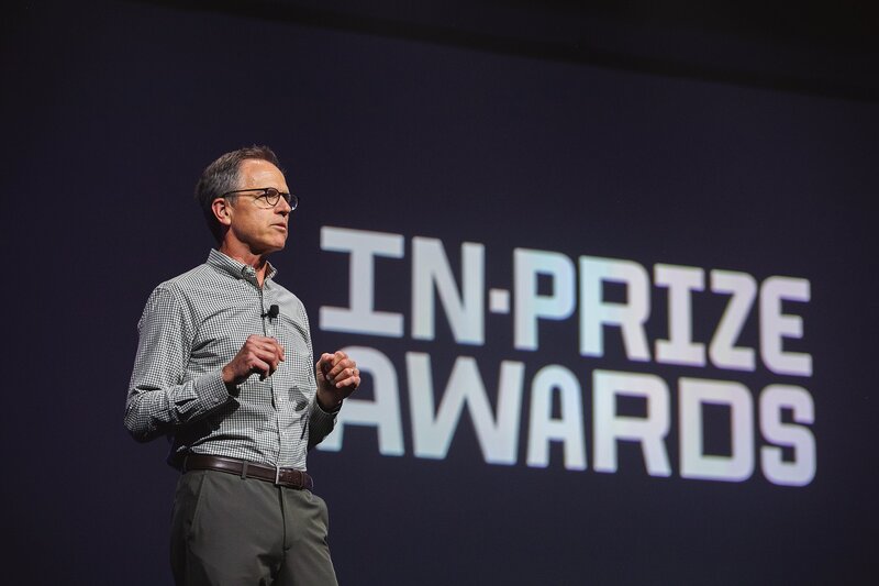  a-professional-keynote-speaker-on-stage-during-a-business-awards-ceremony-in-indiana-with-a-spotlight-and-in-prize-awards-sign-in-the-background-at-the-indiana-convention-center