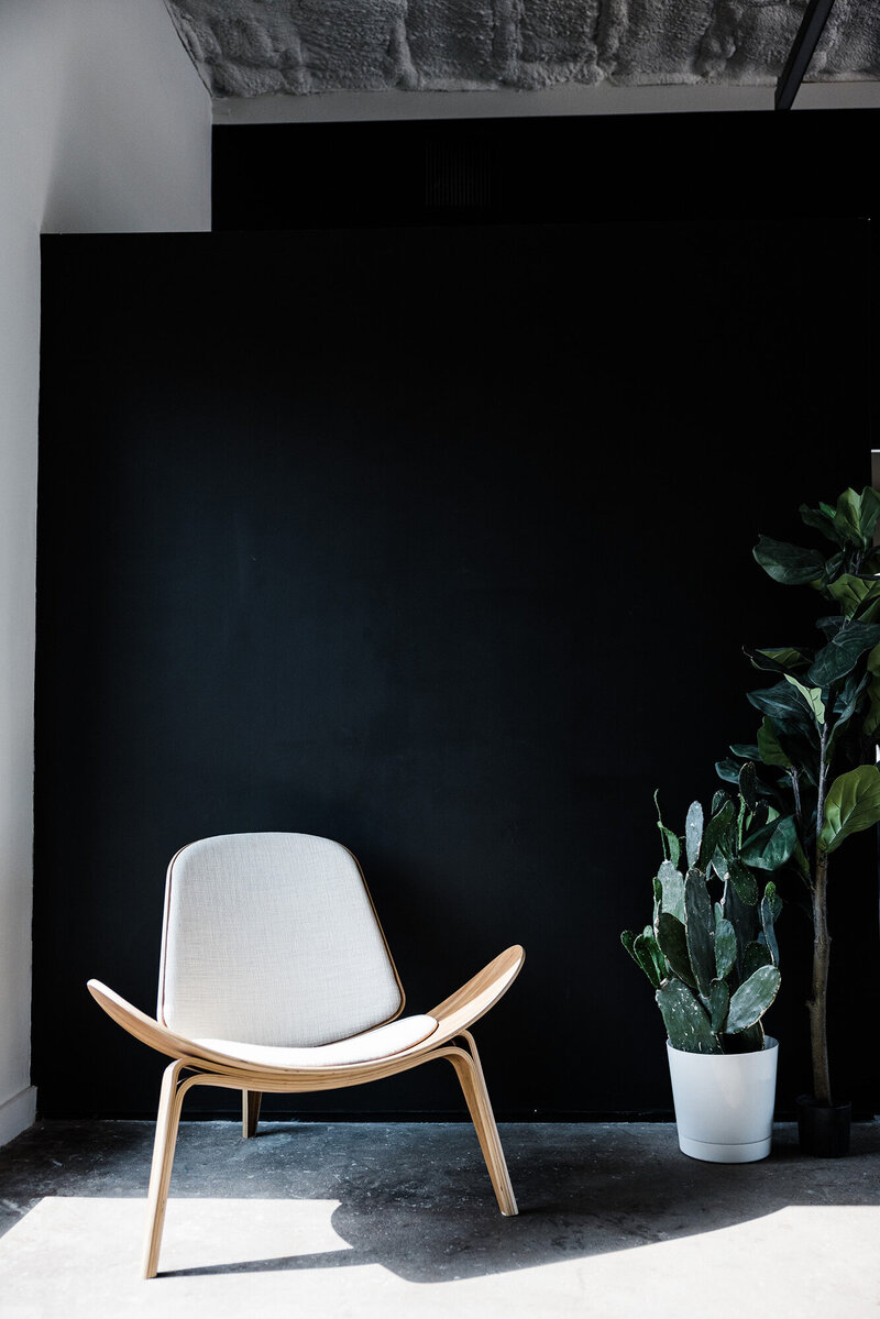 Home photo of a sitting area with a black wall and white chair.