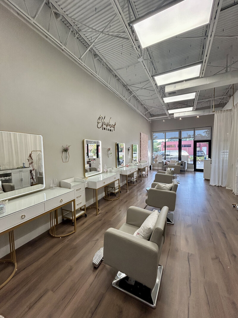 Interior of Blushed Miami salon featuring modern styling stations, elegant mirrors, and a bright, open space designed for luxury beauty services.