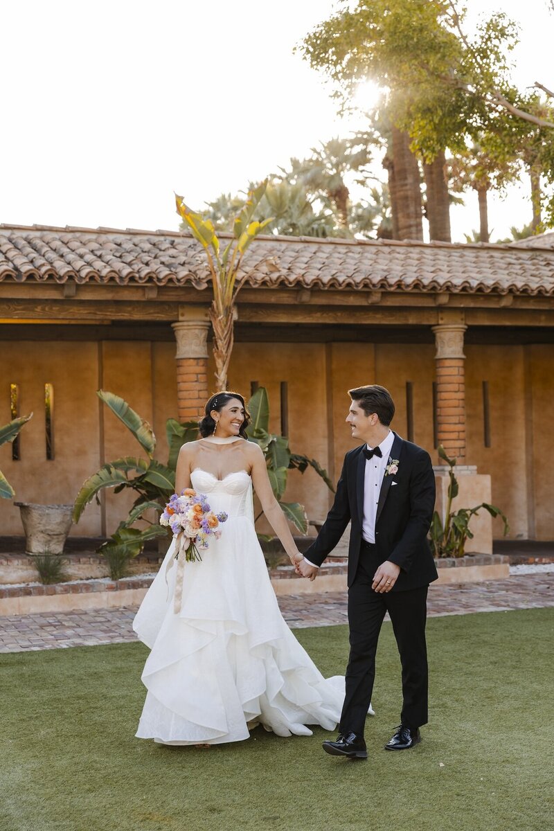 bride and groom hold hands at wedding venue in arizona