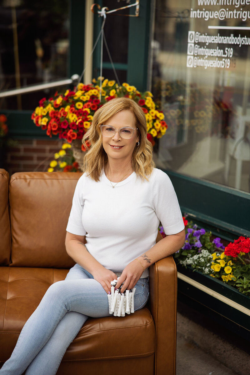 Portrait of Brenda Lucas, senior stylist at Intrigue Salon, standing in front of a natural birch wood backdrop