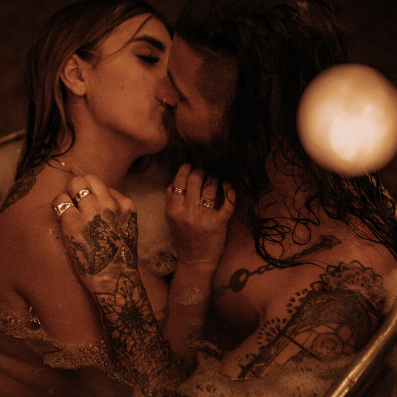 long hair bearded tattooed man kisses wife in arizona boudoir session