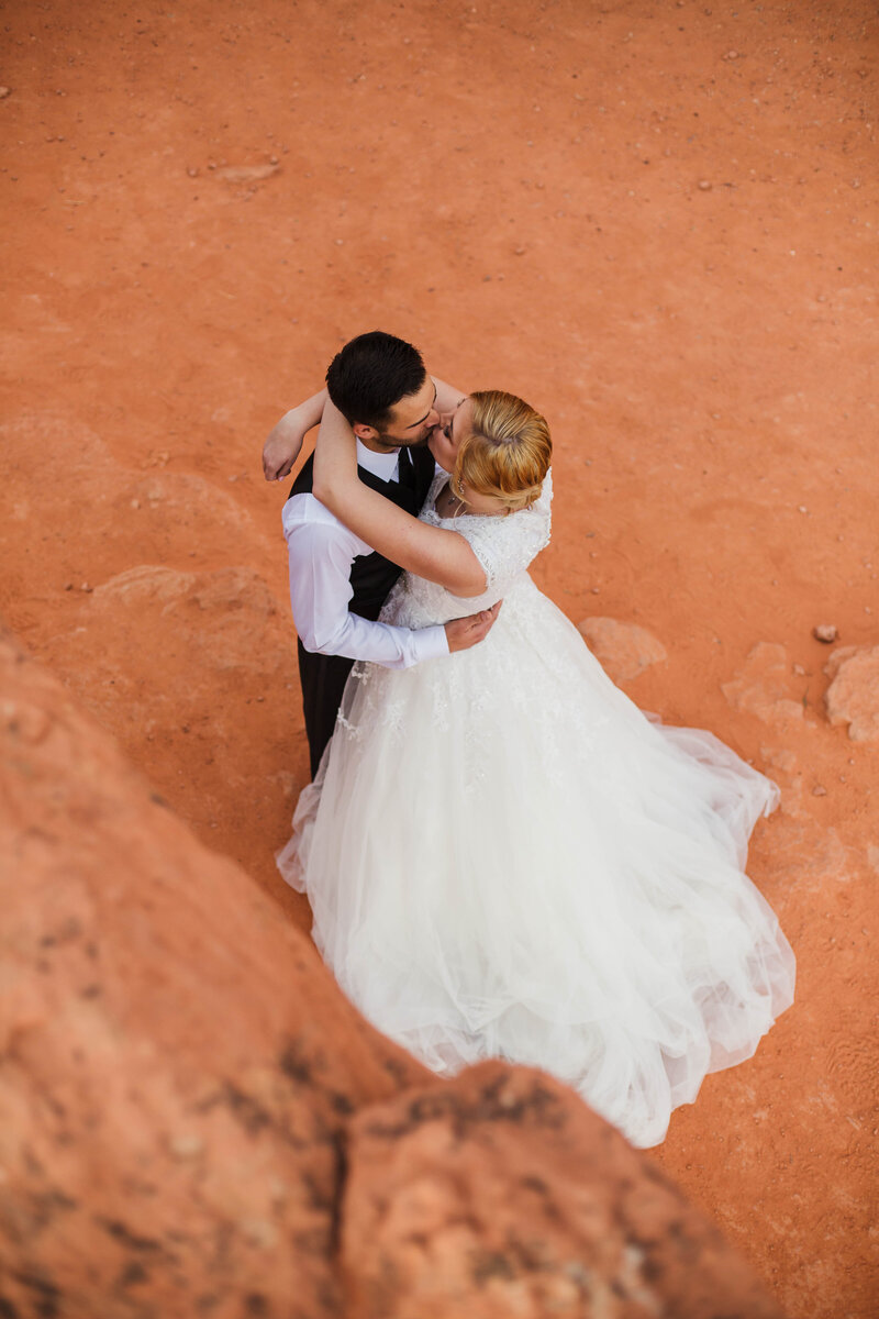 couple kissing in red rock during outdoor bridals