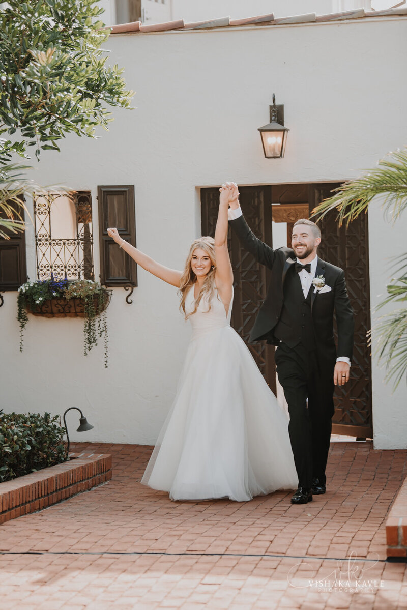 bride and groom smiling while holding their hands in the air