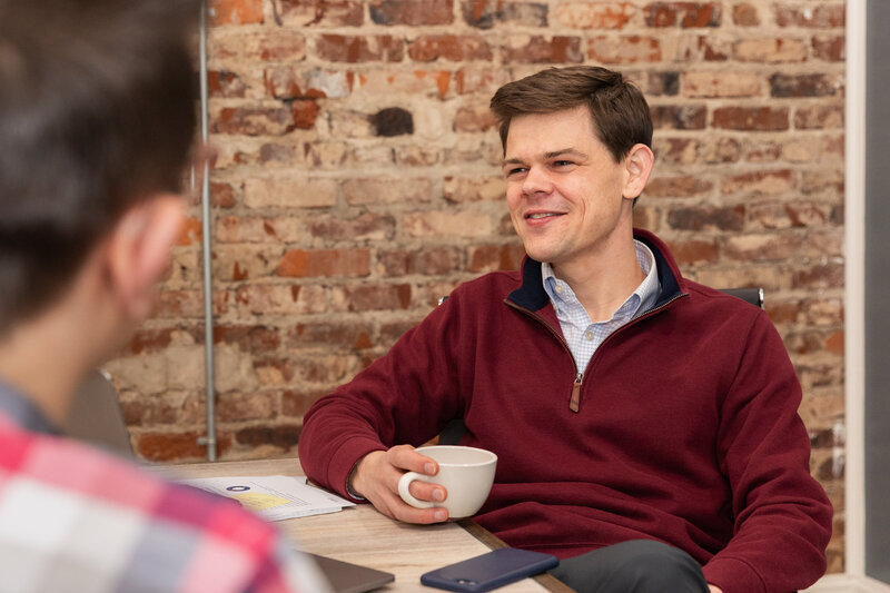 man holding a cup of coffee and listening to someone talking during a business meeting in a conference room Atlanta Brand Photographer
