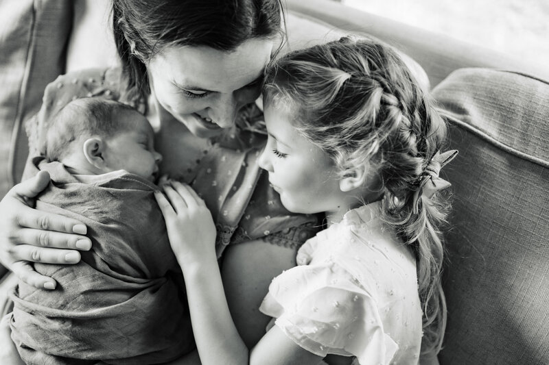 Black and white newborn photo with  mom and big sister