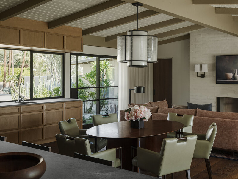 View of kitchen with wood ceilings, dark walnut cabinets, black marble countertops and steel hood designed by Palm Springs architect.