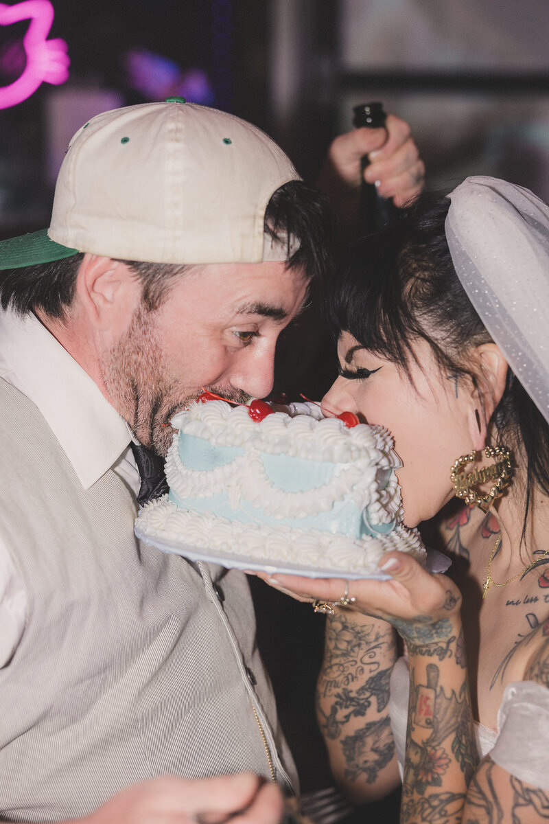 bride and groom take a bite out of their vintage heart cake at Cats Meow after their elopement in Las Vegas