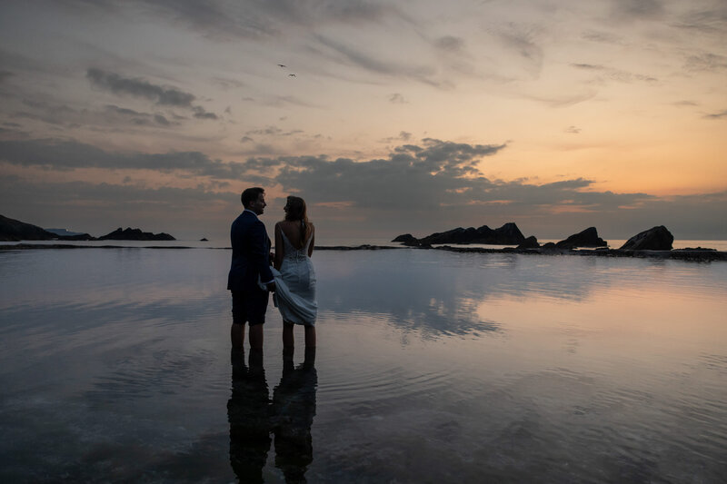 Bride and Groom stood in the sea at Tunnels Beaches Wedding Devon