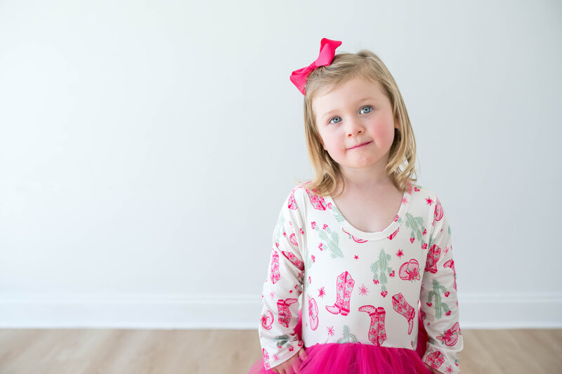 A young girl in a colorful dress, looking candid and natural at the camera for a personality portrait.