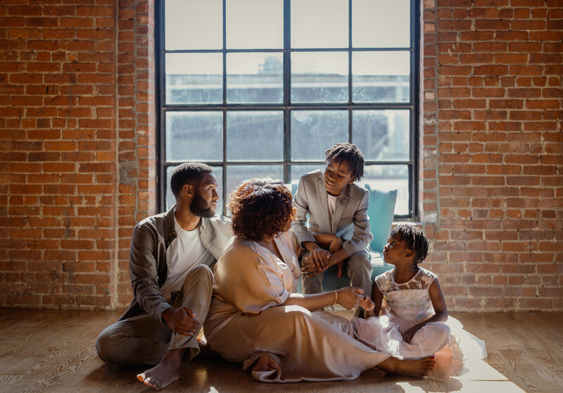 A warm, candid family moment captured in an indoor setting, showcasing parents and children sharing smiles.