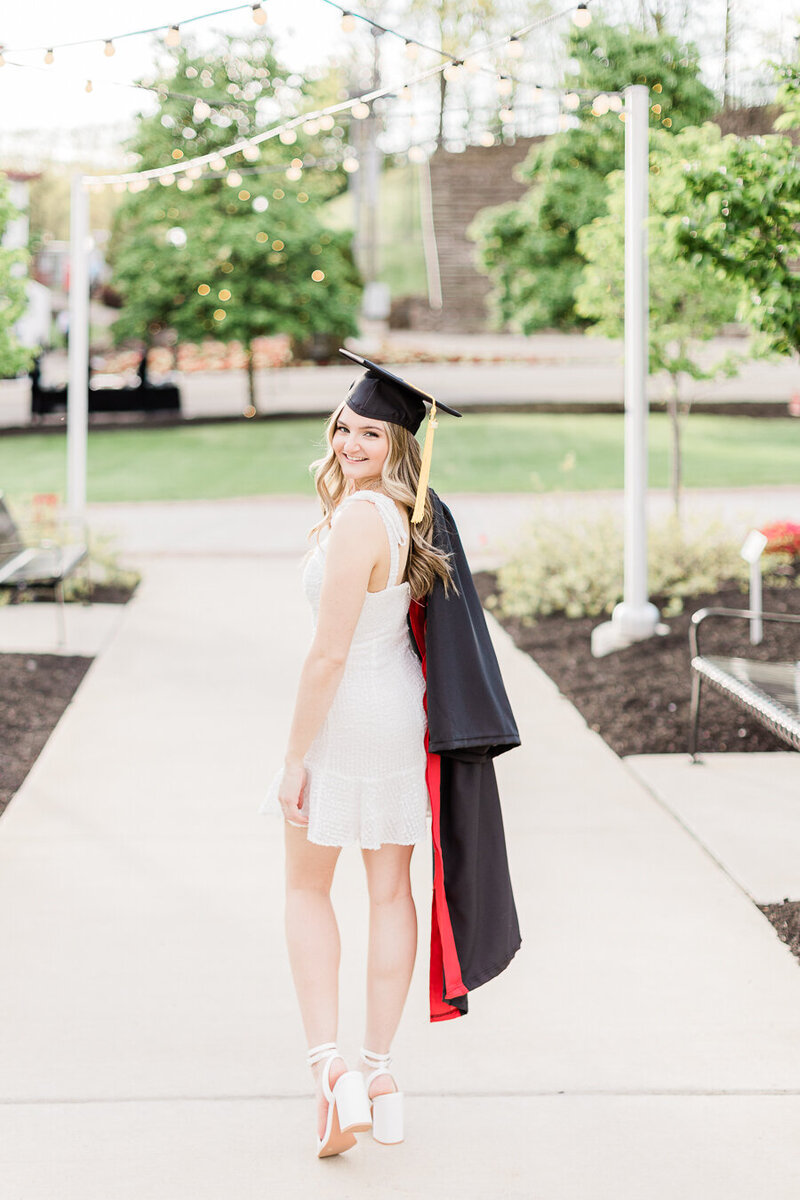 Girl in a white dress holding a graduation gown