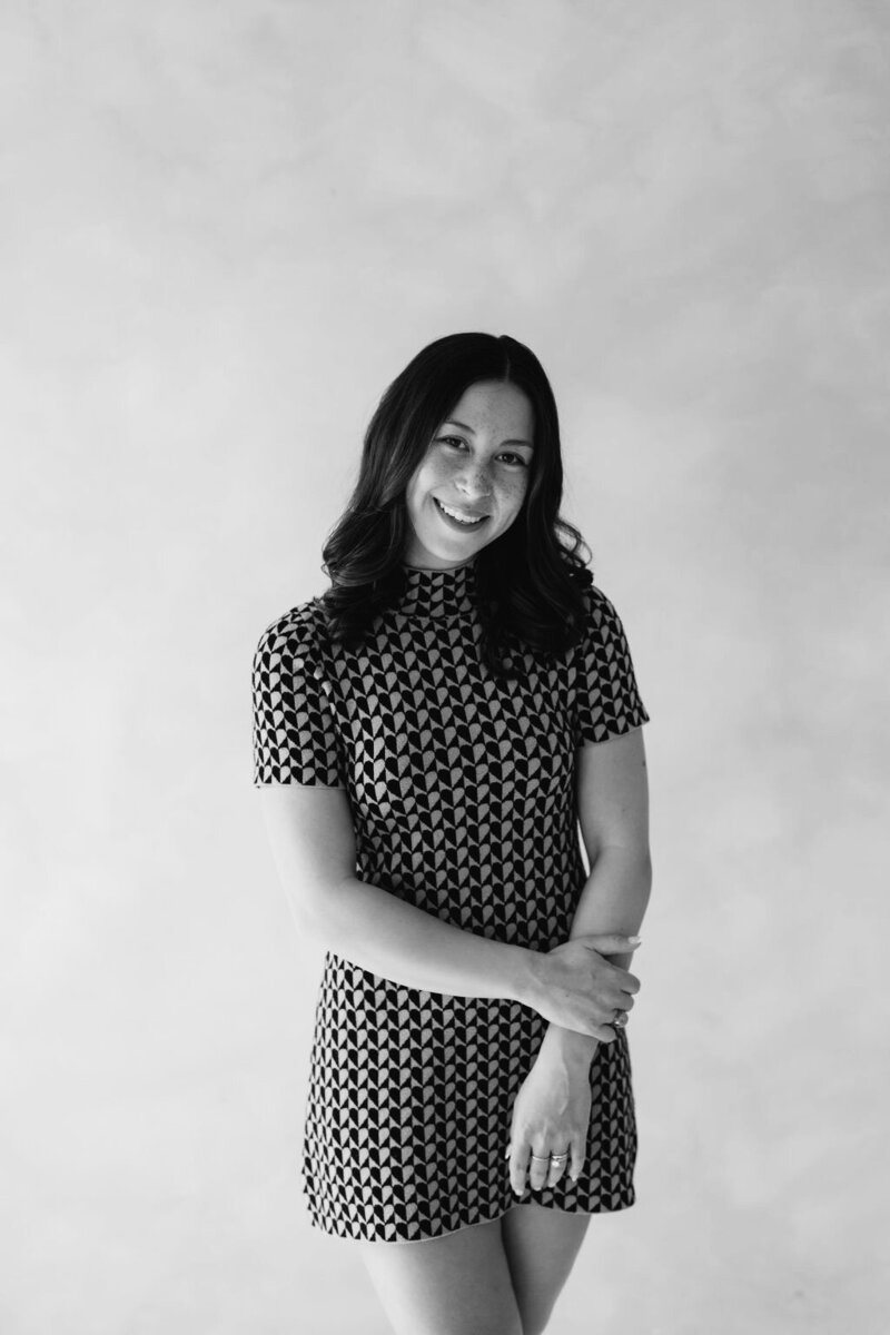 Claire Glynn poses gracefully in a black-and-white portrait beside a beautifully set table. Photo by Logan Alexander