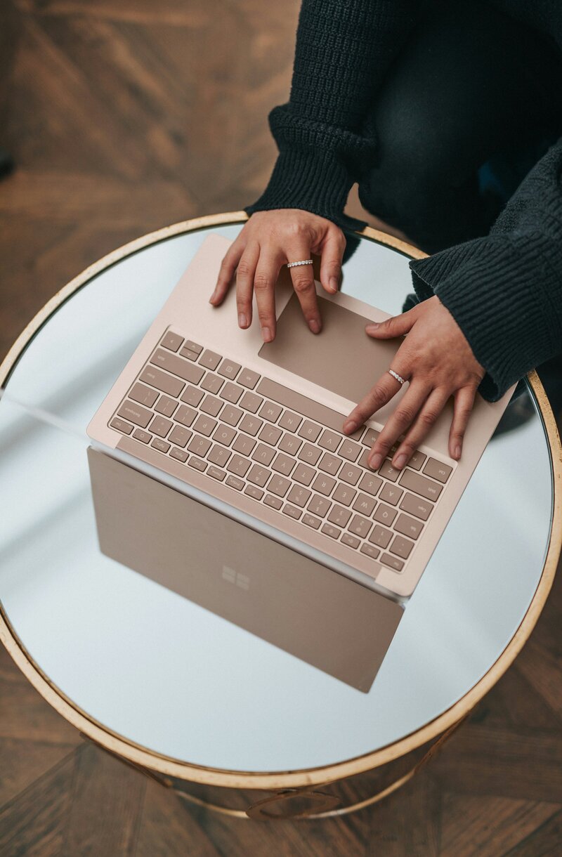 lifestyle mockup of logo Verdant Workshop with a woman working on a laptop. The logo features a tree illustration