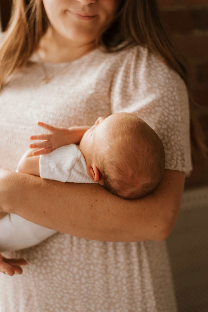 mother holds new baby during newborn shoot in peoria illinois