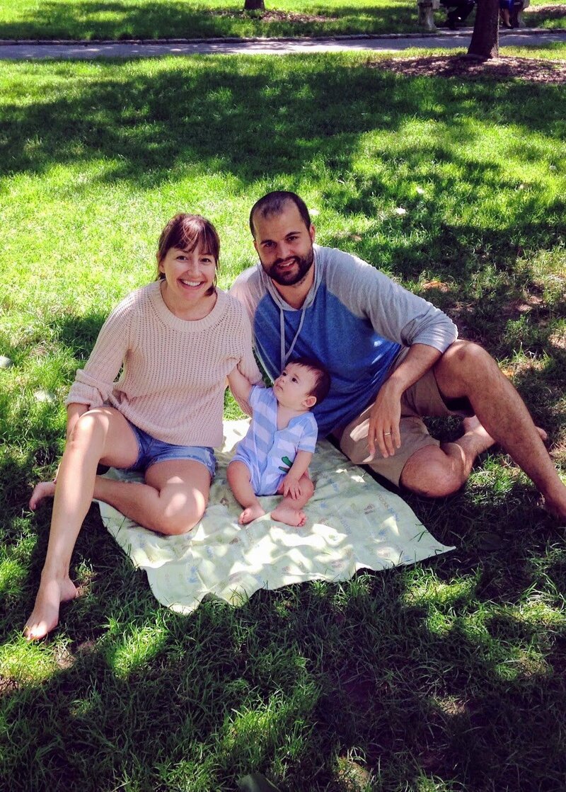 Ali, her husband, and son sitting on a blanket outside