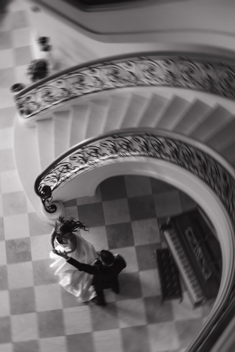 Blurry black & white wedding portrait featuring a stunning staircase and piano at wedding venue, Del Mar Villa