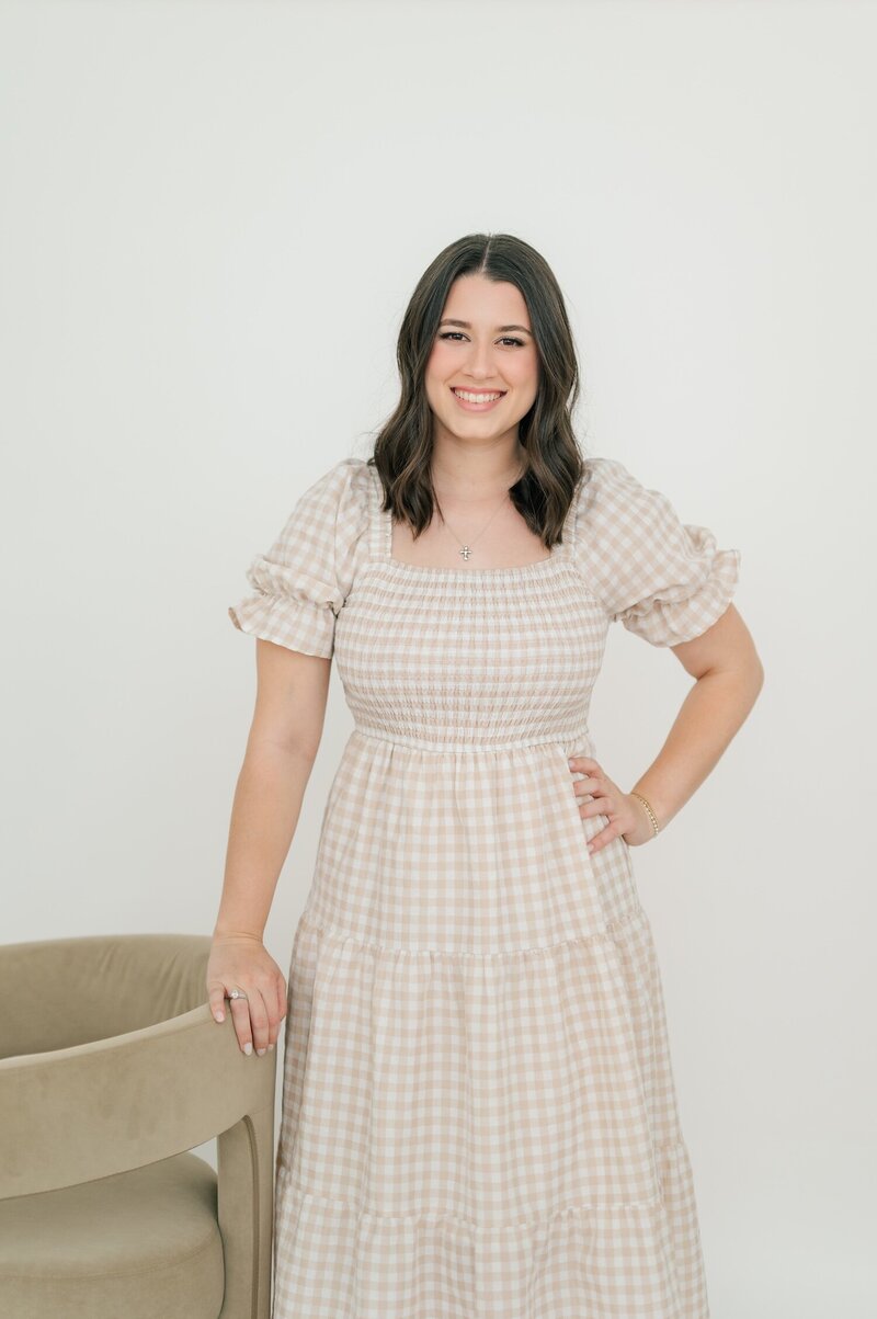 Connecticut wedding photographer Ephe holds her mirrorless camera and smiles to her side on a couch in Hartford, Connecticut. 