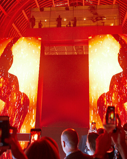 A stage with large video screens and a crowd waiting for the artist, organized by a london event planner