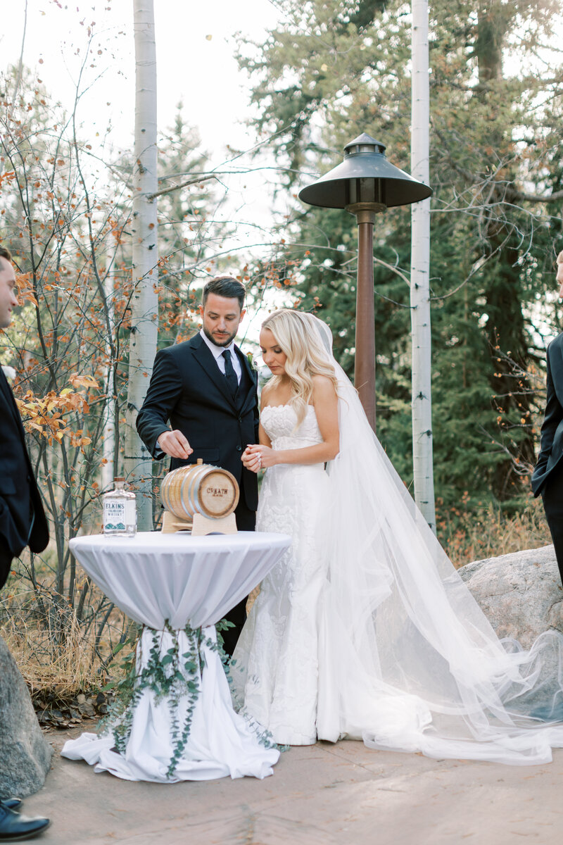 Couple pour Elkins Whiskey in to a wood barrel to age during their wedding ceremony in Vail Colorado at Donovan Pavilion.