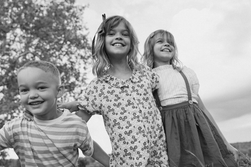 Three kids hugging and playing outside
