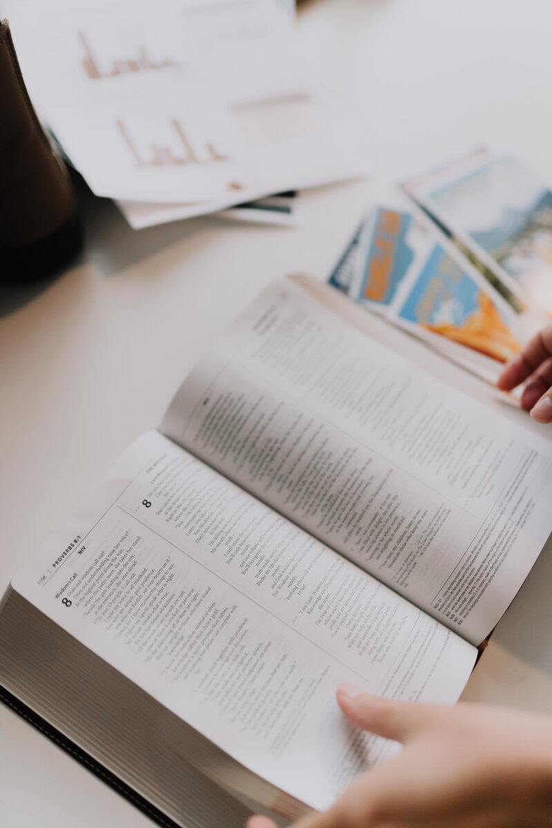 Hands flipping through a Bible on a table