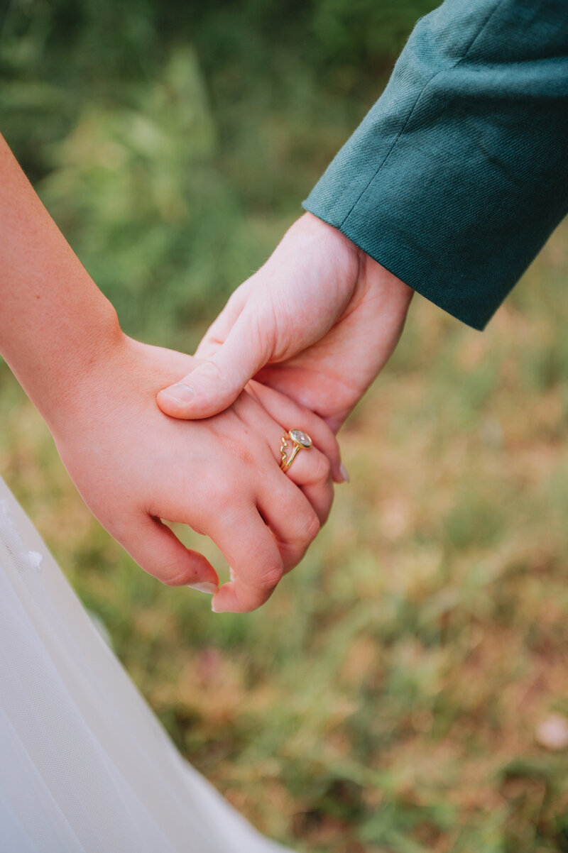 Two people hold hands on their wedding day