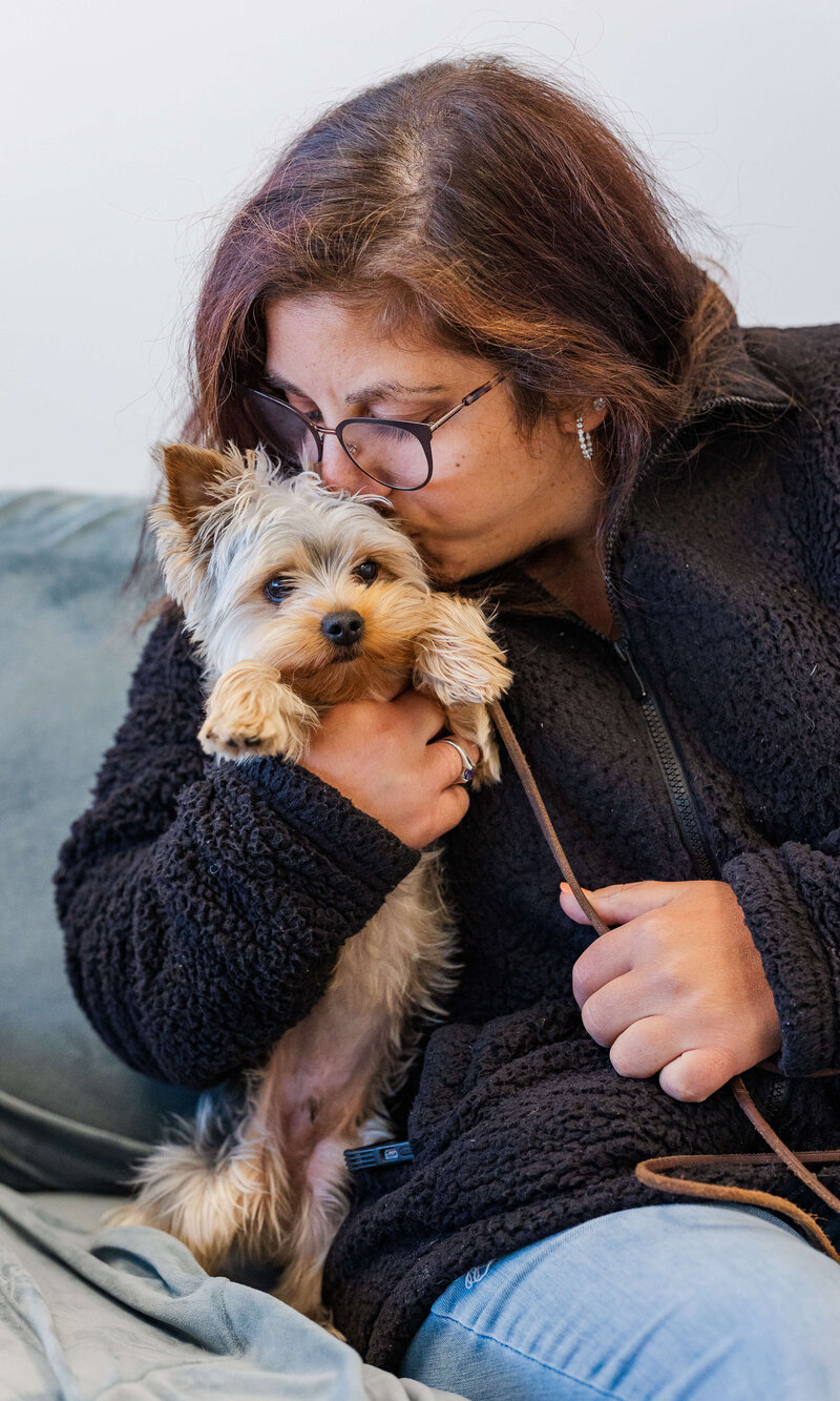 Woman kissing her Yorkie during a Dogology University evaluation session, highlighting their bond
