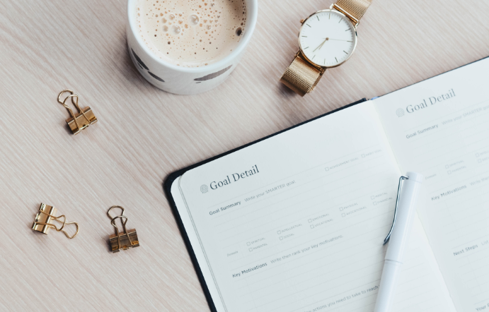 Birds-eye-view of a planner, cup of coffee, and a gold watch